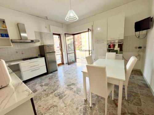 biała kuchnia z białym stołem i krzesłami w obiekcie Greta's Apartment w mieście San Giorgio a Cremano