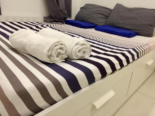 a bed with black and white sheets and towels on it at Icon Residenz Icon City, Petaling Jaya by De Harlequins Guesthouse in Petaling Jaya