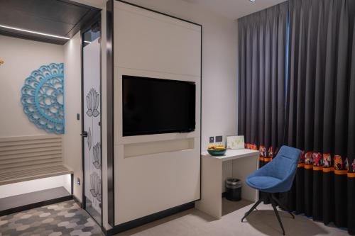 a living room with a tv and a blue chair at Zibe Luxe Kakinada by GRT Hotels in Kākināda
