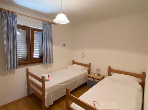 a bedroom with two beds and a window and a table at Villa Oliva in Gruda