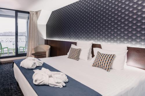 a bedroom with a large bed with towel animals on it at Le Thalassa Hôtel & Spa in Camaret-sur-Mer