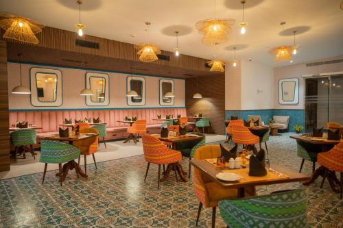 a restaurant with tables and chairs and mirrors at Zibe Luxe Kakinada by GRT Hotels in Kākināda