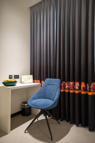 a blue chair sitting in front of a desk at Zibe Luxe Kakinada by GRT Hotels in Kākināda
