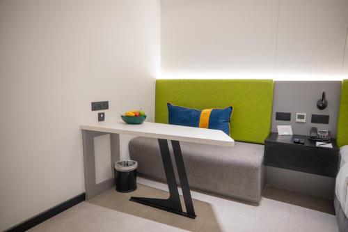 a room with a bed with a table and a green headboard at Zibe Luxe Kakinada by GRT Hotels in Kākināda