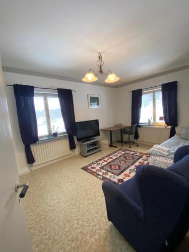 a living room with a bed and a desk and windows at Lägenheter Ljungaverk Apartments Ljungaverk in Ånge