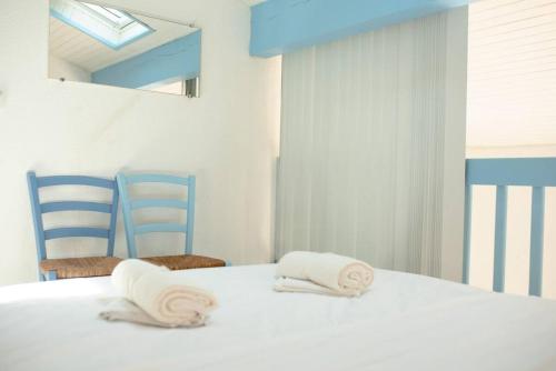 - un lit blanc avec serviettes et 2 chaises bleues dans l'établissement Charmante Villa patio en bordure de forêt, à Capbreton