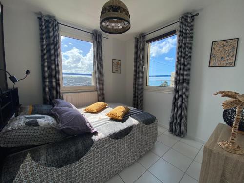 - une chambre avec un lit avec des oreillers et 2 fenêtres dans l'établissement Maison vue mer, port et ville, à Fécamp