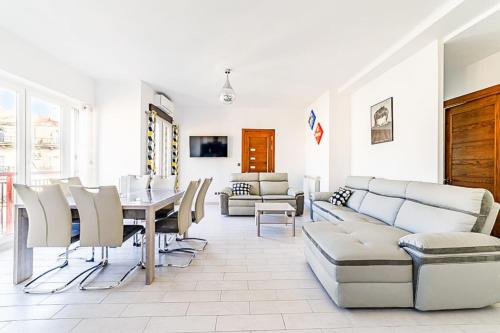 a living room with a couch and a table and chairs at Le Garibaldi - Appart 3 chambres clim avec balcon in Marseille
