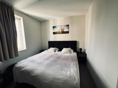 a bedroom with a white bed with two pillows at Oostduinkerke Apartments in Oostduinkerke