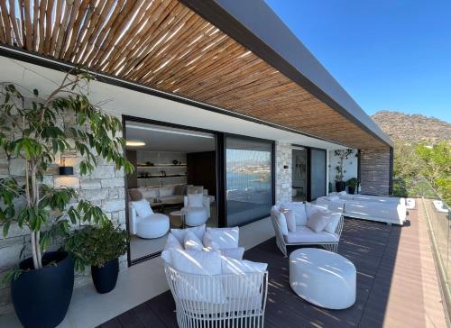 un patio con sillas blancas, mesas y ventanas en Mystique Luxury Suite en Achlia
