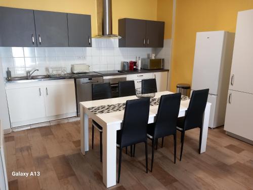une cuisine avec une table blanche et des chaises noires dans l'établissement T3 pratique, Garage gratuit, Esprit Auber, à Béziers