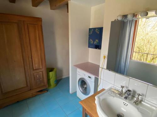 une salle de bain avec un lavabo et une machine à laver dans l'établissement Maison de campagne bucolique et ressourçante, à Sainte-Hélène-du-Lac