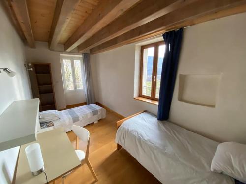 une chambre avec deux lits, une table et un bureau dans l'établissement Maison de campagne bucolique et ressourçante, à Sainte-Hélène-du-Lac