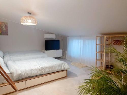 a white bedroom with a bed and a television at Jin House Incheon Geomamstation in Incheon