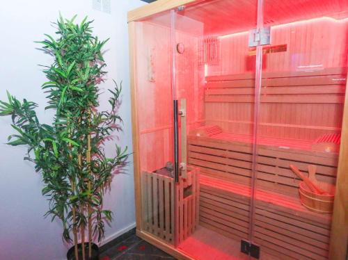 eine Dusche mit Glastür neben einer Pflanze in der Unterkunft CasaLova in Épinay-sur-Seine