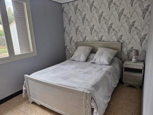 a bedroom with a white bed with a wall at Maison le murier in Aubignan
