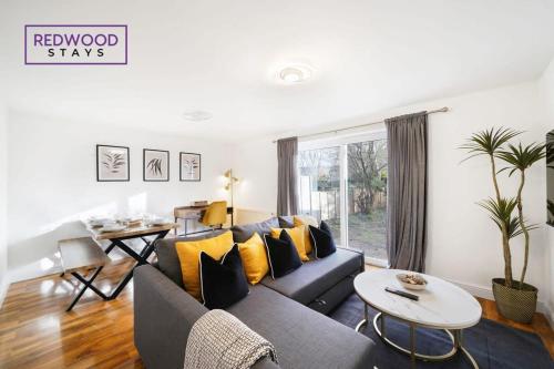 a living room with a blue couch and yellow pillows at Cosy 3-Bedroom Serviced House with Free WiFi and Parking By Redwood Stays in Farnborough