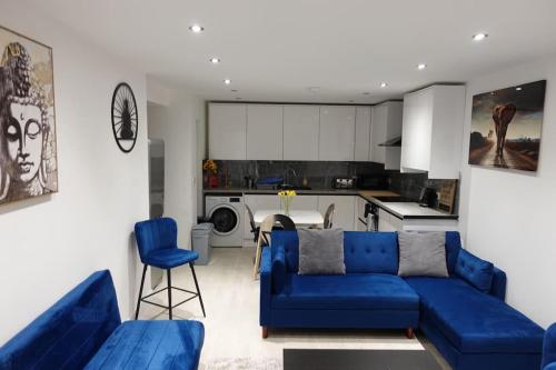 a living room with a blue couch and a kitchen at KYOTO HOUSE CENTRAL DERBY I 2 BEDROOMS, SPACIOUS, WARM & NEW with NETFLIX in Derby