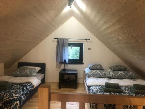 a attic room with two beds and a window at Domek Zgredek in Żywiec