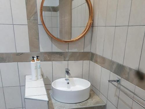een badkamer met een witte wastafel en een spiegel bij Marloth Cottage in Marloth Park
