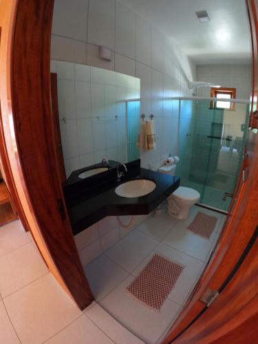 a bathroom with a sink and a toilet and a mirror at Bahia Haus Don Pietro in Canavieiras
