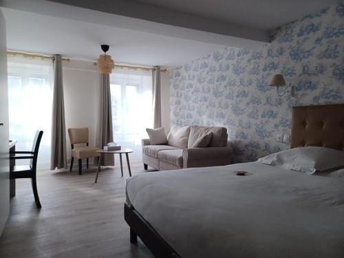 a bedroom with a bed and a living room with a couch at Grand Hôtel de l'Europe - Morlaix Centre in Morlaix
