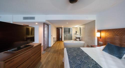 a bedroom with a bed and a television and a bathroom at Riu Montego Bay - Adults Only - All Inclusive in Montego Bay