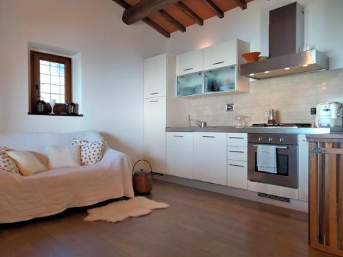 una cocina con armarios blancos y un sofá en una habitación en Casa Benucci Oliveta Tuscany, en Pulicciano