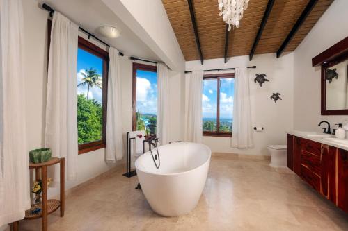 baño con una gran bañera blanca y ventanas en Tet Rouge Resort, en Soufrière