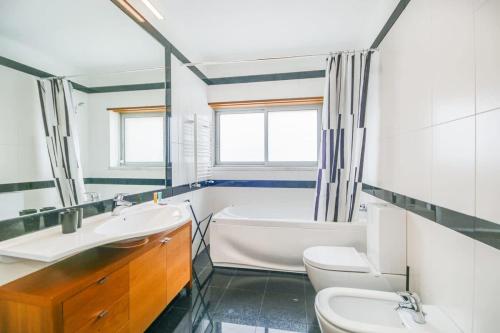 uma casa de banho com uma banheira, um lavatório e um WC. em Admiral House Estoril em Estoril