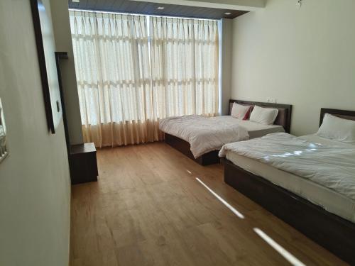 a bedroom with two beds and a large window at Hotel ananya fairview in Khātu