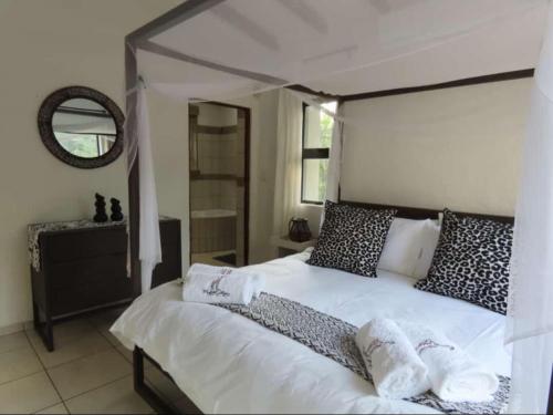 um quarto com uma cama branca e um espelho em Marloth Cottage em Marloth Park