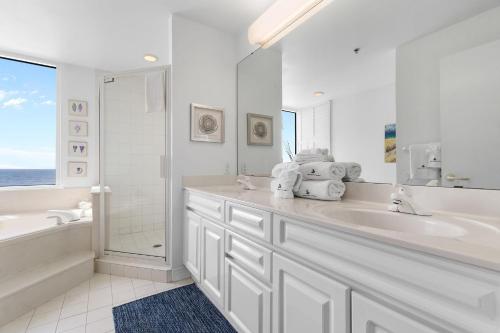 La salle de bains blanche est pourvue d'une baignoire, d'un lavabo et d'une douche. dans l'établissement Beach Colony Tower 8B, à Perdido Key