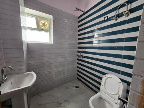 a bathroom with a toilet and a sink and a window at homeystay urbandream service apartment in Faridabad