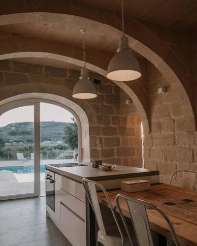 a kitchen with a table and chairs and a stone wall at Blissful 4-bedroom villa with pool in Għasri