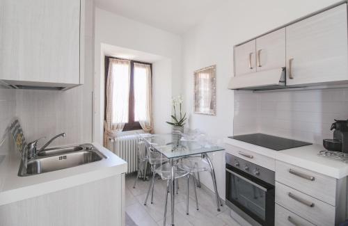 een witte keuken met een wastafel en een tafel bij Appartamento Francisca in Domaso