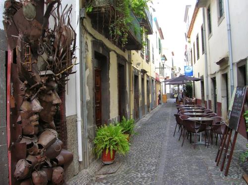 an alley with tables and chairs on a street at Guest house Santa Maria in Funchal