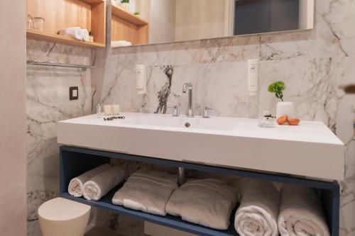 a bathroom with a sink and a pile of towels at Hotel Croatia in Cavtat