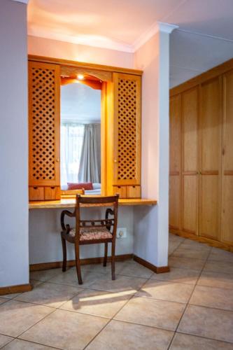 a chair sitting in a room with a mirror at Waters on Willows in Pretoria