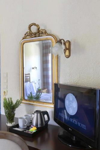 a desk with a television and a mirror on a wall at Aneroussa Beach Hotel in Batsi