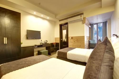 a hotel room with two beds and a television at Saltstayz Thyme - New Friends Colony in New Delhi