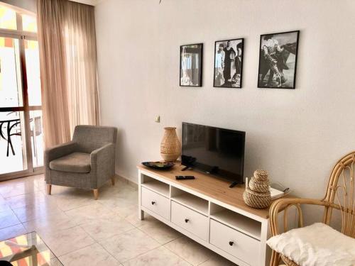 a living room with a flat screen tv and a chair at Beautiful bungalow on the Torrox-Costa boulevard! in Málaga
