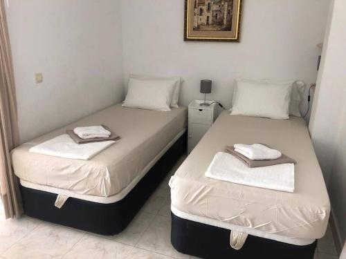 two beds in a room with white sheets and towels at Beautiful bungalow on the Torrox-Costa boulevard! in Málaga