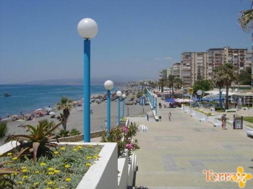 a beach with blue poles and people on the beach at Beautiful bungalow on the Torrox-Costa boulevard! in Málaga