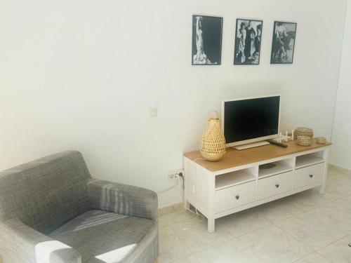 a living room with a couch and a television on a cabinet at Beautiful bungalow on the Torrox-Costa boulevard! in Málaga