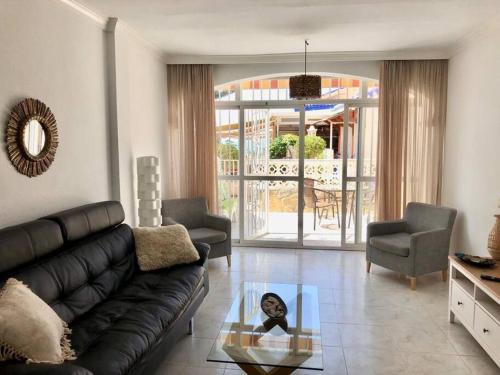 a living room with a black couch and a glass table at Beautiful bungalow on the Torrox-Costa boulevard! in Málaga