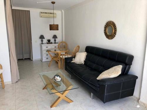 a living room with a black couch and a table at Beautiful bungalow on the Torrox-Costa boulevard! in Málaga