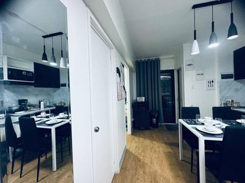 a kitchen and dining room with white tables and chairs at Mactan Oasis Garden/ 2 Bedrooms/ Near Airport in Mactan