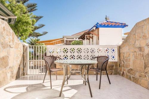 a table and chairs on a patio with a fence at Beautiful bungalow on the Torrox-Costa boulevard! in Málaga