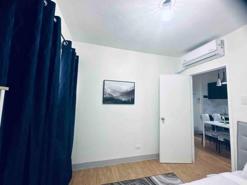 a bedroom with a blue curtain and a room with a table at Mactan Oasis Garden/ 2 Bedrooms/ Near Airport in Mactan